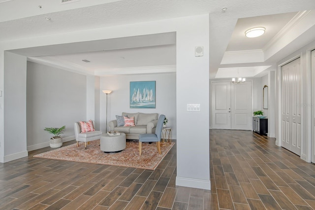 living area with wood tiled floor, a raised ceiling, and a notable chandelier