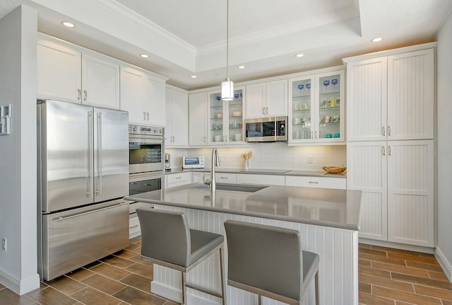 kitchen featuring stainless steel appliances, a sink, white cabinets, wood tiled floor, and a raised ceiling