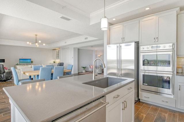 kitchen featuring stainless steel appliances, ornamental molding, wood tiled floor, open floor plan, and a sink