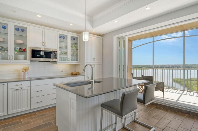 kitchen with wood tiled floor, stainless steel microwave, a sink, and a water view