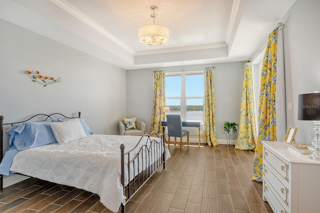 bedroom with wood finish floors, a raised ceiling, crown molding, and baseboards