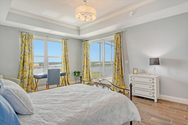 bedroom featuring wood finish floors, baseboards, access to exterior, a raised ceiling, and crown molding