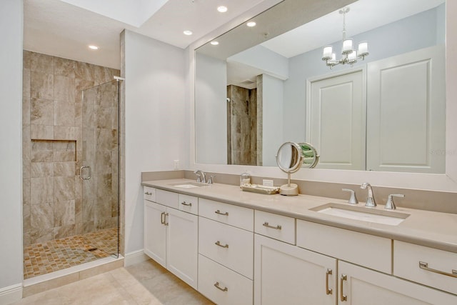 full bathroom with double vanity, a notable chandelier, a shower stall, and a sink