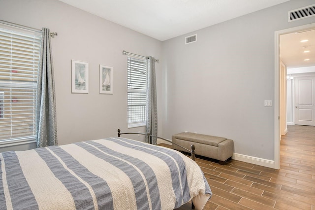 bedroom featuring wood finish floors, visible vents, and baseboards