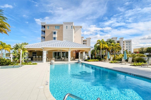 community pool with fence, a ceiling fan, and a patio