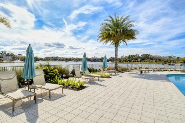 view of patio featuring a water view, fence, and a community pool