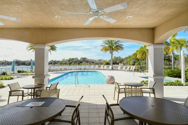 community pool featuring fence, outdoor dining area, a ceiling fan, and a patio