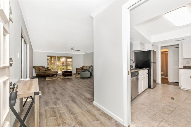 kitchen featuring appliances with stainless steel finishes, white cabinetry, sink, ceiling fan, and light hardwood / wood-style floors