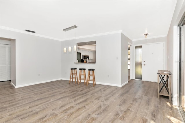 unfurnished living room with ornamental molding and wood-type flooring