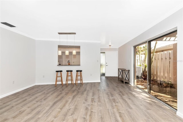 unfurnished living room with crown molding and light hardwood / wood-style flooring