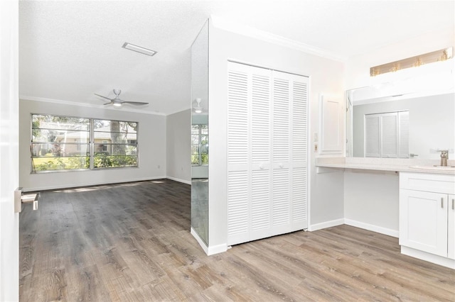 hallway with ornamental molding, sink, a textured ceiling, and light wood-type flooring