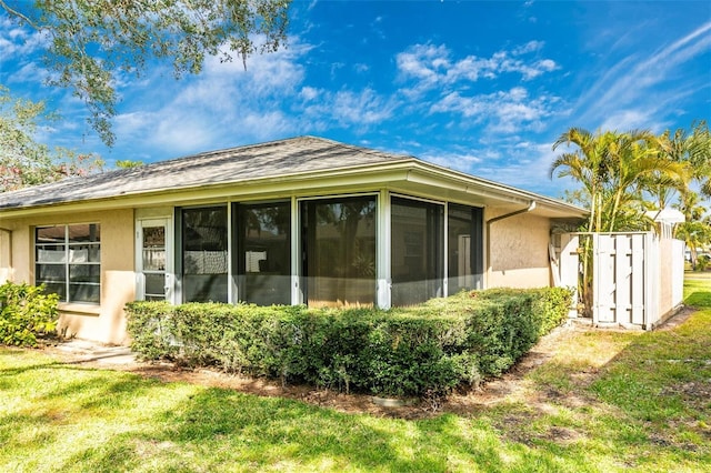 view of property exterior featuring a sunroom and a lawn