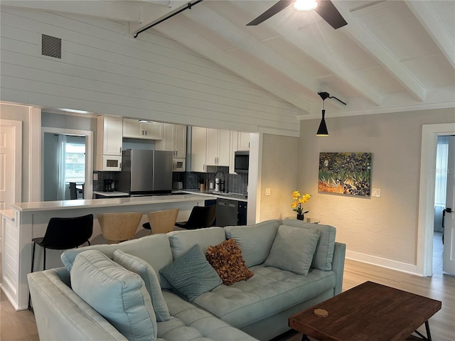 living room featuring high vaulted ceiling, beamed ceiling, sink, ceiling fan, and light hardwood / wood-style floors