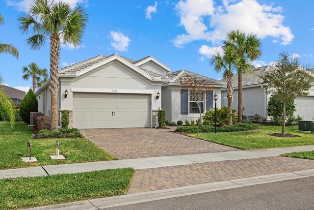 view of front of house with a garage, central AC unit, and a front lawn