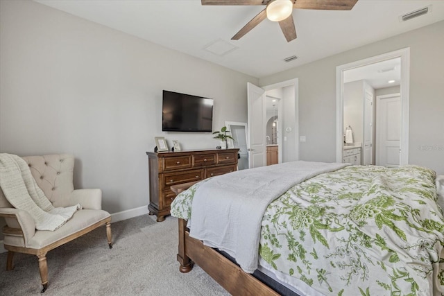 bedroom with ceiling fan, light colored carpet, and ensuite bath