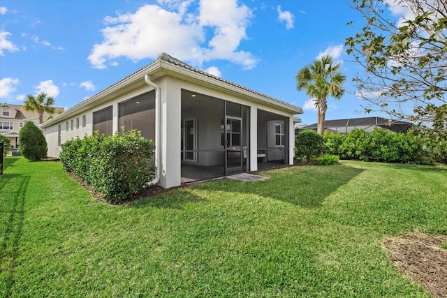 rear view of property with a yard and a sunroom