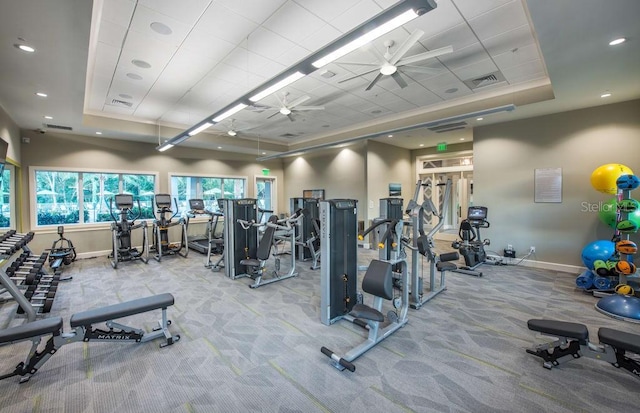 workout area with light carpet, ceiling fan, and a tray ceiling