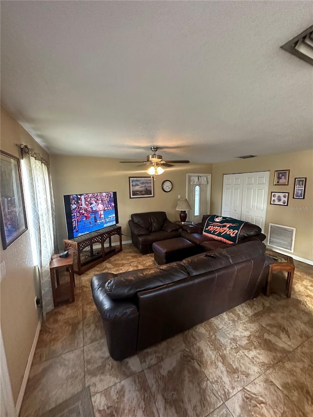 living room with ceiling fan and a textured ceiling