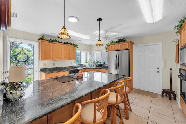 kitchen with pendant lighting, a breakfast bar area, dark stone counters, light tile patterned floors, and stainless steel appliances