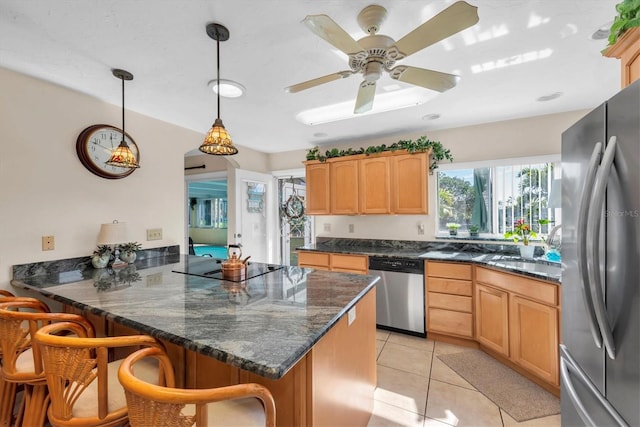 kitchen with a kitchen bar, decorative light fixtures, dark stone countertops, kitchen peninsula, and stainless steel appliances