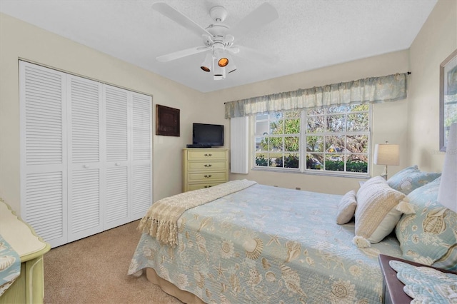 bedroom featuring light carpet, a textured ceiling, ceiling fan, and a closet