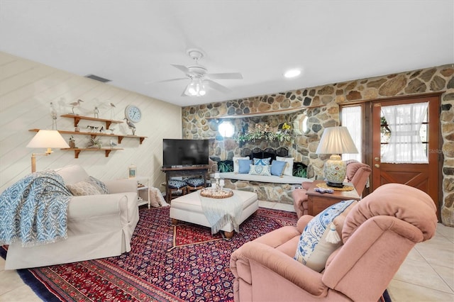 living area featuring tile patterned floors, visible vents, and ceiling fan