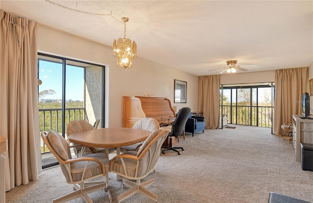 carpeted dining area featuring ceiling fan with notable chandelier and a textured ceiling