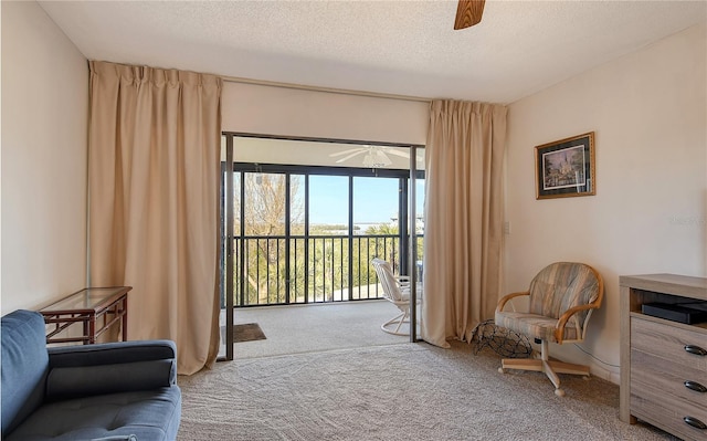 living area with ceiling fan, carpet flooring, and a textured ceiling