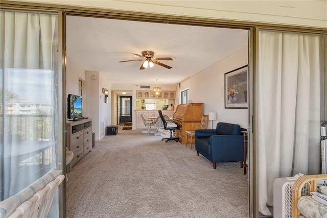 living area featuring light carpet, ceiling fan, and a textured ceiling