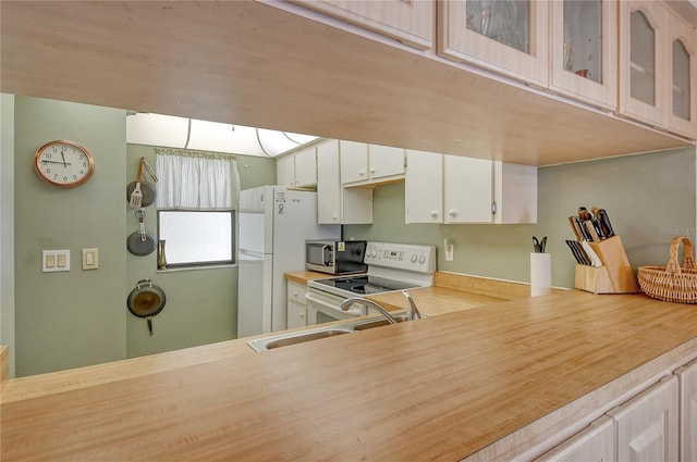 kitchen featuring white appliances, sink, and white cabinets