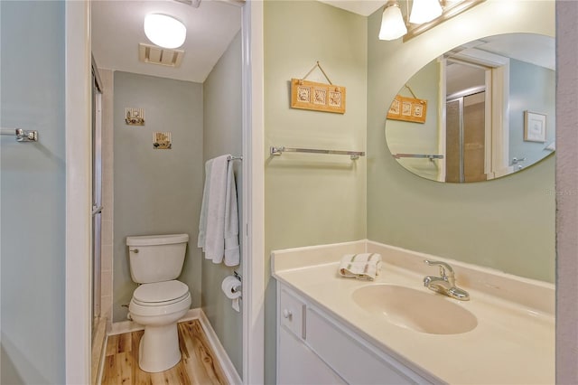 bathroom with vanity, wood-type flooring, a shower with shower door, and toilet