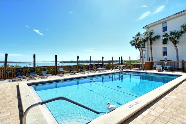 view of swimming pool with a water view and a patio area