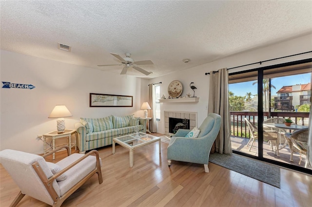 living room with a fireplace, a wealth of natural light, light hardwood / wood-style floors, and a textured ceiling