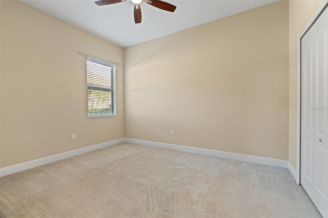 unfurnished bedroom featuring light carpet, a closet, and ceiling fan