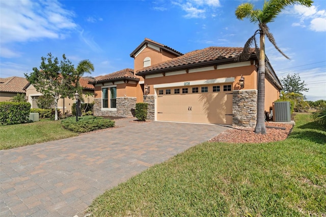 mediterranean / spanish-style house featuring a garage, a front yard, and central air condition unit