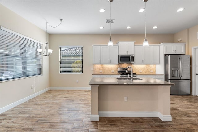 kitchen with white cabinetry, stainless steel appliances, sink, and hanging light fixtures