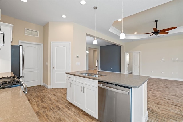 kitchen with sink, white cabinetry, appliances with stainless steel finishes, a tray ceiling, and pendant lighting