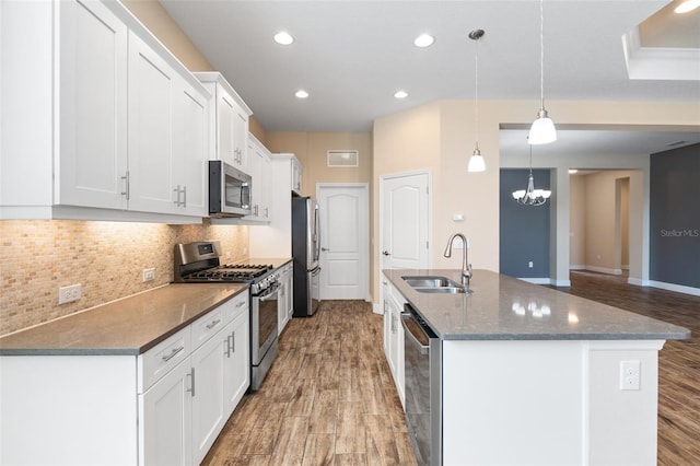 kitchen featuring pendant lighting, sink, stainless steel appliances, an island with sink, and white cabinets