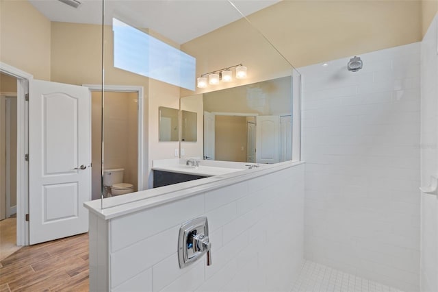 bathroom featuring tiled shower, wood-type flooring, toilet, and vanity