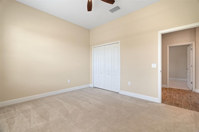 unfurnished bedroom featuring ceiling fan, light colored carpet, and a closet