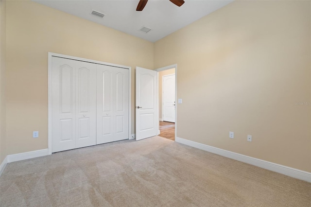 unfurnished bedroom featuring light colored carpet, a closet, and ceiling fan