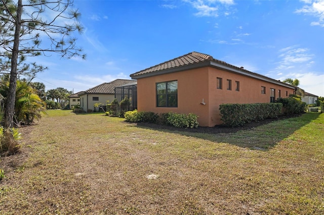 view of side of home with a yard and a lanai