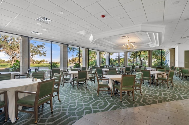 interior space featuring a notable chandelier, a raised ceiling, and a healthy amount of sunlight