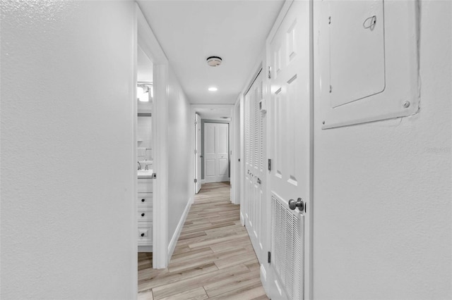 corridor featuring electric panel and light wood-type flooring