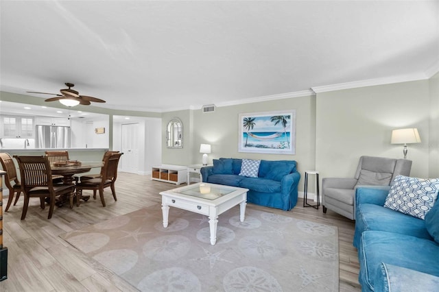 living room with ornamental molding, ceiling fan, and light hardwood / wood-style flooring