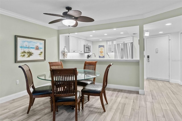 dining room with ornamental molding, sink, and light hardwood / wood-style floors