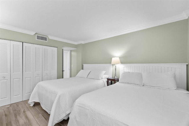 bedroom with crown molding, light hardwood / wood-style floors, and a closet