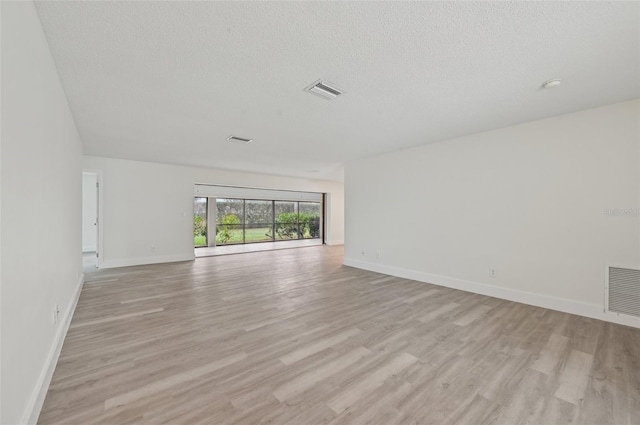 spare room with light hardwood / wood-style flooring and a textured ceiling