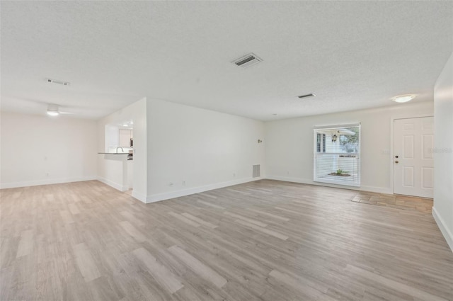 unfurnished living room with a textured ceiling and light hardwood / wood-style floors