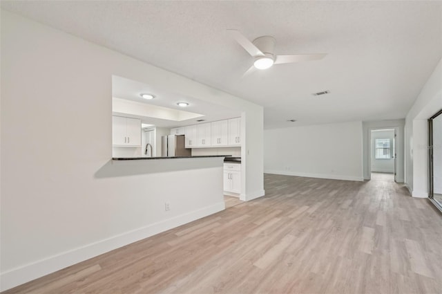 unfurnished living room featuring ceiling fan, sink, and light hardwood / wood-style floors